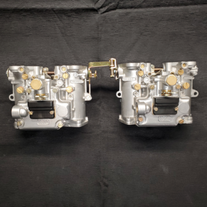 The image depicts a Dellorto DHLA 45 Pair Carburetor, primarily made of shining silver metal with golden accents and screws after having been reassembled.