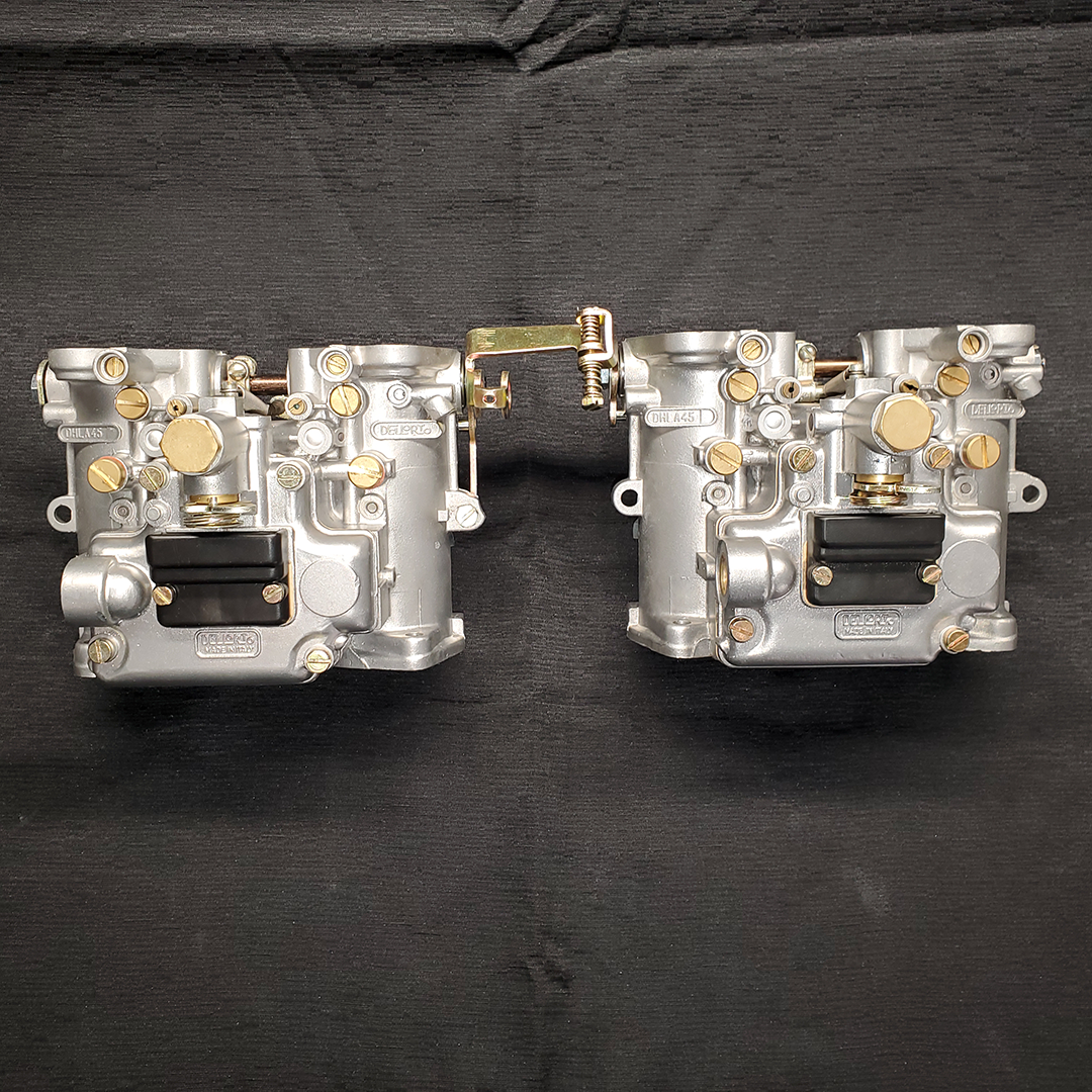 The image depicts a Dellorto DHLA 45 Pair Carburetor, primarily made of shining silver metal with golden accents and screws after having been reassembled.